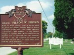Historical marker dedicated to Lieutenant Wilson W. Brown, with text detailing his contributions and background, surrounded by trees and a grassy area.