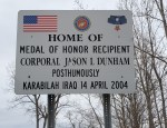 Sign honoring Medal of Honor recipient Corporal Jason L. Dunham, located in his hometown, with American flags and military insignia.