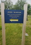 A sign indicating the grave of John McBrugh, labeled as a soldier of the Union Army, with an arrow pointing to the direction of the grave.