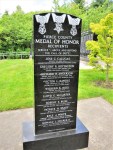 A monument dedicated to Medal of Honor recipients from Franklin County, featuring engraved names and three medal designs at the top, set in a green park environment.